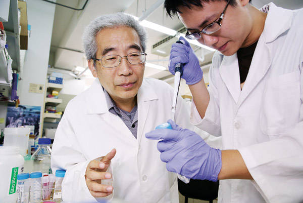 Chang Chung-i (left) and grad student Lin Jianzhu use a probe to pick up a bit of crystallized protein, which they will examine using X-ray -crystallography.
